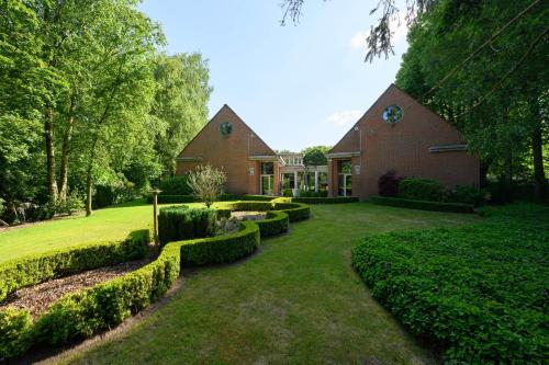 a house with a yard with hedges in front of it at Hotel Watermolen Le Mirage in Kasterlee