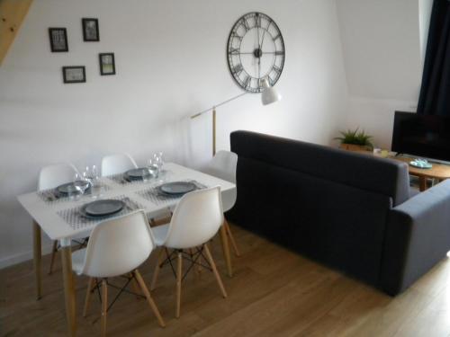 une salle à manger avec une table, des chaises et une horloge dans l'établissement Apartment Lille - Proche métro - Stationnement gratuit, à Lille