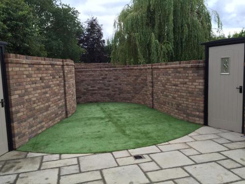 a garden with a brick fence and green grass at Shrewsbury Cottage in Shrewsbury