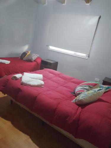 a bedroom with two beds with red sheets and a window at Sosiego Patagonico dpto A in Perito Moreno