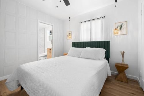 ein weißes Schlafzimmer mit einem großen Bett und einem Fenster in der Unterkunft Bakersfield Sunset Stay in Bakersfield