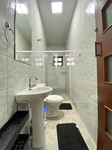 a white bathroom with a sink and a toilet at Casa Pazim in Itanhaém
