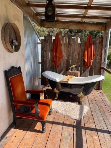 a bath tub sitting on a deck with a chair at Galway Cottage in Willunga