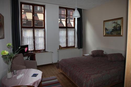 Schlafzimmer mit einem Bett, einem Tisch und Fenstern in der Unterkunft Ferienwohnung im Stieg 4 in Quedlinburg