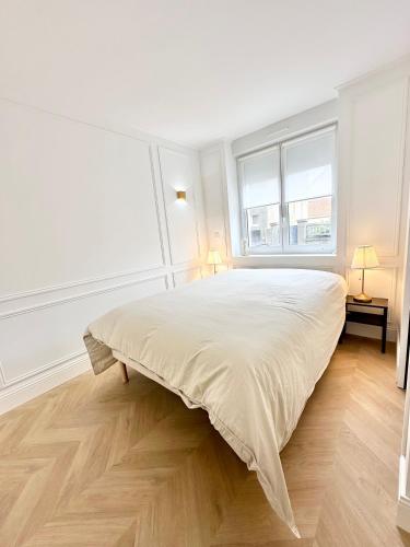 une chambre blanche avec un grand lit et deux fenêtres dans l'établissement L'Opéra - Le Portel, à Le Portel