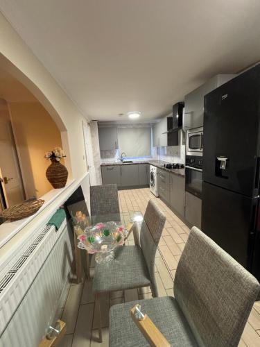 a kitchen with a table and chairs and a black refrigerator at Cosy 2bed home near NEC BHX HS2 Business Park in Marston Green