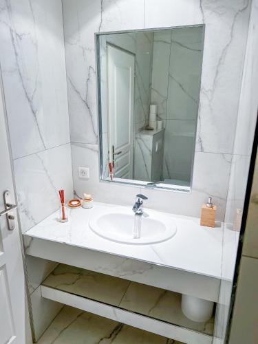 une salle de bain blanche avec un lavabo et un miroir dans l'établissement Havre de paix, à Sussargues