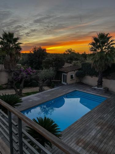 - une piscine sur une terrasse avec un coucher de soleil en arrière-plan dans l'établissement Havre de paix, à Sussargues
