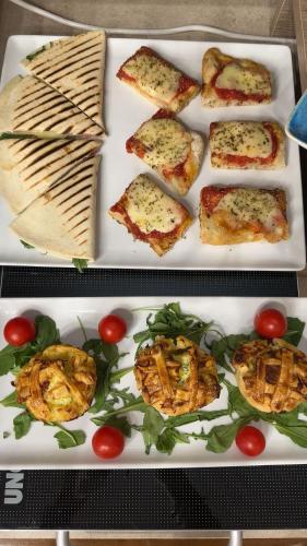 a plate of food with pizza and tomatoes on it at Ines Apartments in Giardini Naxos