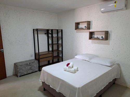 a bedroom with a bed with white sheets and a shelf at Lar do Patacho in Pôrto de Pedras