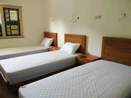 ein Schlafzimmer mit zwei Betten und einem Fenster in der Unterkunft Ndalem Kadipaten Homestay in Ngabean