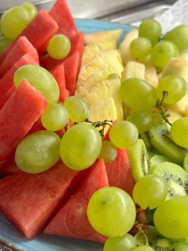 a plate of fruit with grapes and watermelon at Ines Apartments in Giardini Naxos