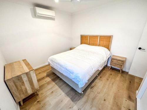 a bedroom with a white bed and a wooden floor at Williamstown Townhouse in Williamstown