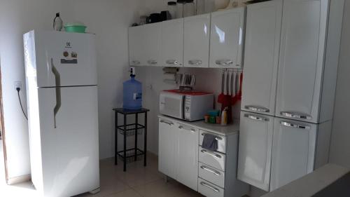 eine Küche mit weißen Geräten und einem weißen Kühlschrank in der Unterkunft Casa de Praia Toca da Onça in São Miguel do Gostoso