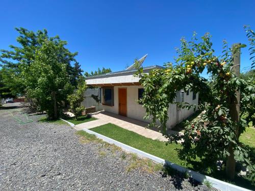 a small white house with trees in front of it at Cabañas Villa Alegre in Lago Rapel