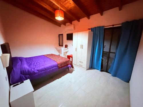 a bedroom with a purple bed and blue curtains at Valle Serrano in Mina Clavero