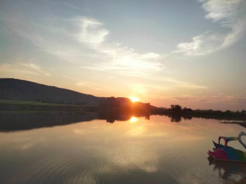 a sunset on a river with a boat in the water at ลุงไซยเดอะแคมป์ in Ban Wang Hin Ngon