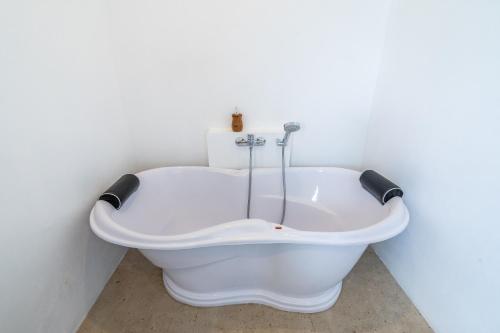 a bath tub in a bathroom with a white wall at Akasia Hill Villas in Nusa Dua