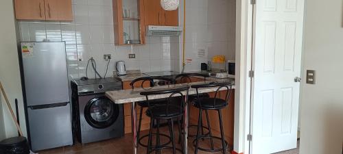 cocina con fogones y encimera con taburetes en Departamento Balneario Pelluco, en Puerto Montt