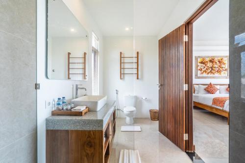 a bathroom with a sink and a toilet and a bed at Akasia Hill Villas in Nusa Dua