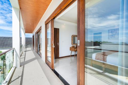 a balcony with glass doors and a view of the ocean at Akasia Hill Villas in Nusa Dua