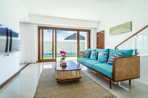 a living room with a blue couch and a table at Akasia Hill Villas in Nusa Dua