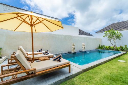 an umbrella and chairs next to a swimming pool at Akasia Hill Villas in Nusa Dua