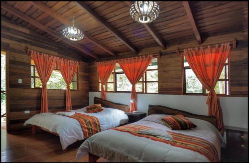 2 Betten in einem Zimmer mit Holzwänden und Fenstern in der Unterkunft Rio Quijos EcoLodge in El Chaco