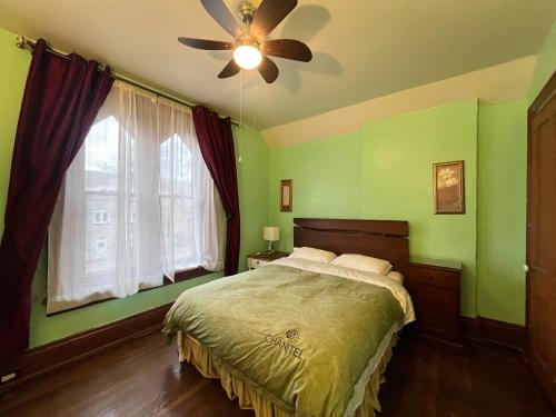a bedroom with green walls and a bed with a ceiling fan at THE RED STAR ROOM A in Niagara Falls