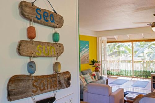 a living room with wooden signs that say sea salt and surf at Beautiful Beachfront Townhouse 3bdrm 2bth with outside day bed OR overflow bedroom in Maunaloa