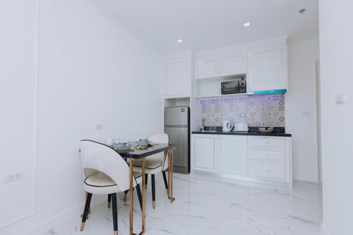 a kitchen with white cabinets and a table and chairs at The Empire Tower k in Jomtien Beach