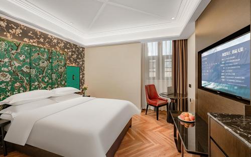 una camera da letto con un letto grande e una TV a schermo piatto di Metropolo Hotel Xuzhou High-speed Railway Station Jinlonghu a Xuzhou