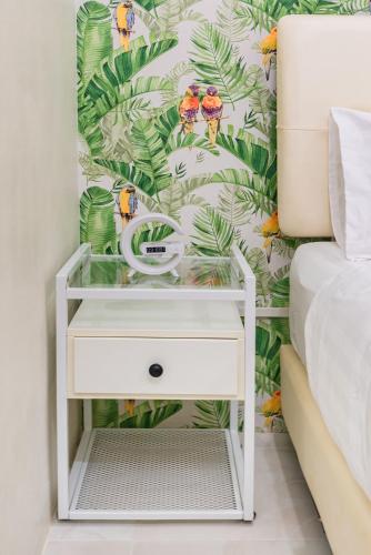 a bedroom with a bed and a white nightstand with a drawer at Songbird Suites in Ban Khlong Haeng