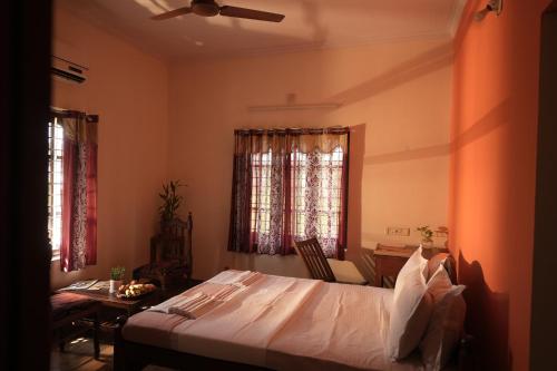 a bedroom with a bed and a table and two windows at Namasthe Ayurveda and Yoga Retreat Cochin in Nedumbassery