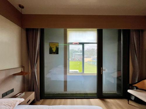 a bedroom with a glass door with a view of a baseball field at Grace Hotel in Honiara