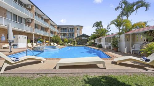 a swimming pool with lounge chairs and a building at Ocean Parade 20 - Ocean Parade 20 - Resort access, BBQ, Surf Beach in Coffs Harbour