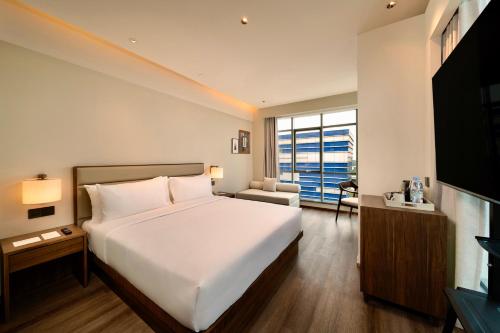 a bedroom with a large white bed and a television at Model J Hotel Jakarta Soekarno - Hatta Airport 曼居酒店 雅加达苏加诺哈达机场店 in Gardu