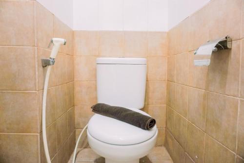 a bathroom with a toilet with a black towel at Enjoy Living and Warm Studio at Serpong Garden Apartment By Travelio in Tangerang