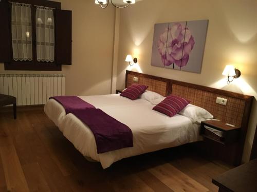 a bedroom with a large bed with two purple pillows at Hostal Otsoa in Ezcároz