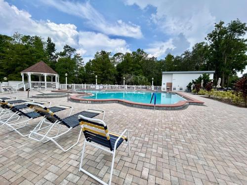 une piscine avec des chaises et un gazebo dans l'établissement Your home away from home! Entire cottage- Disney, à Kissimmee
