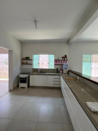 a large kitchen with white cabinets and a stove at Casa com 4 quartos em Cananeia in Cananéia