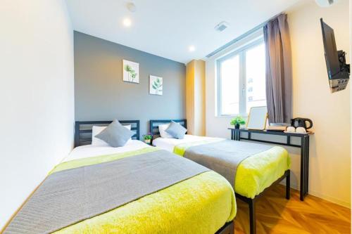 a hotel room with two beds and a television at JA Hotel Tennoji in Osaka