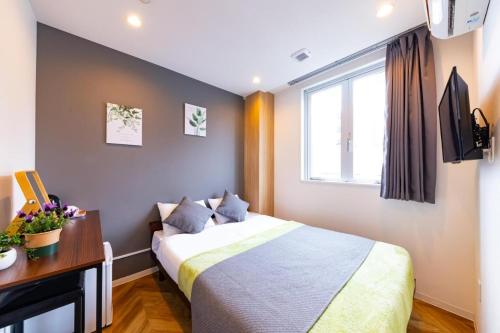 a bedroom with a bed and a desk and a window at JA Hotel Tennoji in Osaka