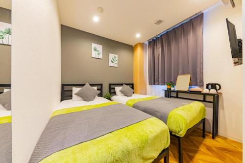 a bedroom with two beds and a laptop on a desk at JA Hotel Tennoji in Osaka