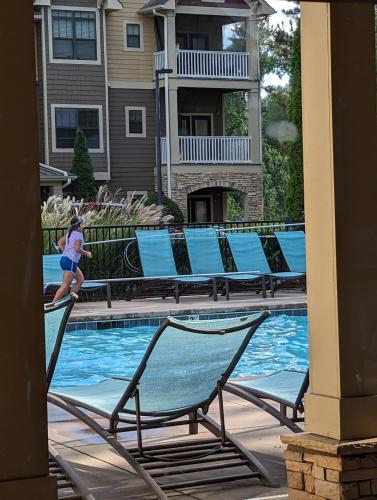 a woman is walking by a swimming pool with chairs at Home away from Home - Book Friday and Saturday Get Sunday Free! Sleeps 7 Immediate Availability! Beautiful Gated Community in Charlotte