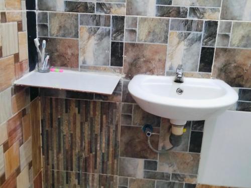a bathroom with a white sink and a tiled wall at Penginapan Bunga Sonsang kamar Family Tripel in Sungaidaras