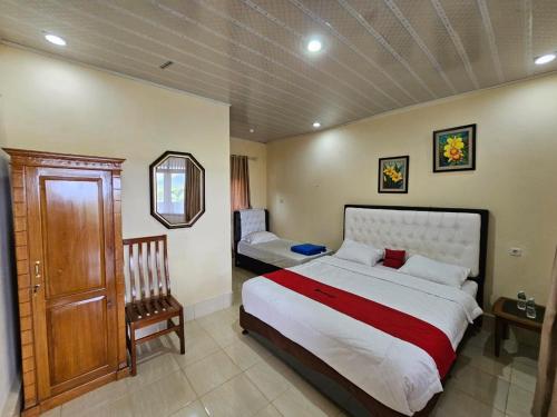 a bedroom with a large bed and a chair at Penginapan Bunga Sonsang kamar Family Tripel in Sungaidaras