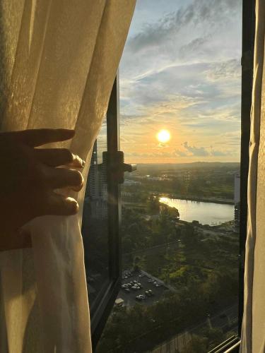 a person looking out of a window at the sunset at Legoland-8min walk at Kairos Comfort Spacious Suite for Families 1-12pax in Nusajaya
