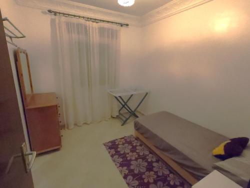 a small bedroom with a bed and a table at Quiet and beautiful apartment near the airport in Tangier