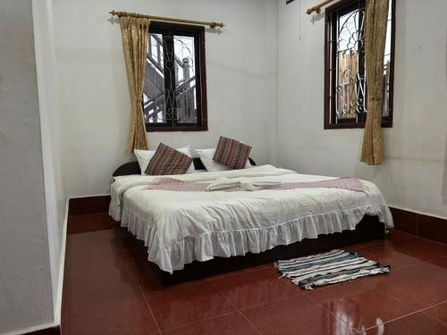 a bedroom with a bed and two windows at Maophasok river side hotel in Luang Prabang